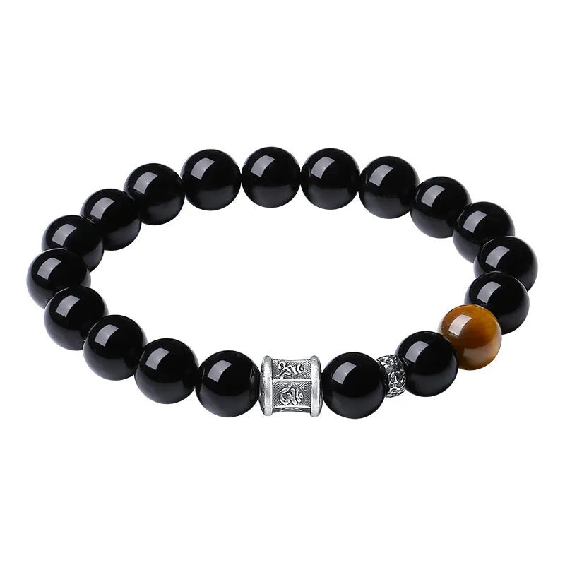 Men's black obsidian bracelet with 10mm prayer wheel beads and silver accents showing hand-woven construction