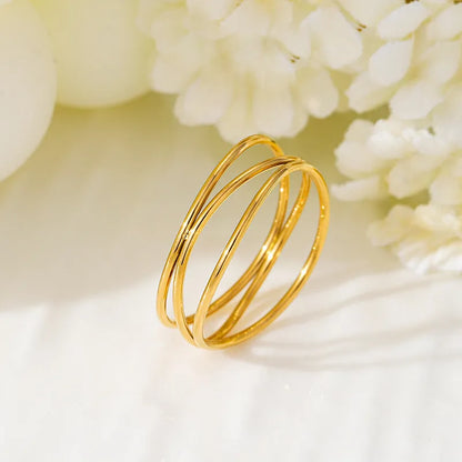 Gold titanium steel geometric coil ring with three-layer design on a model's finger.