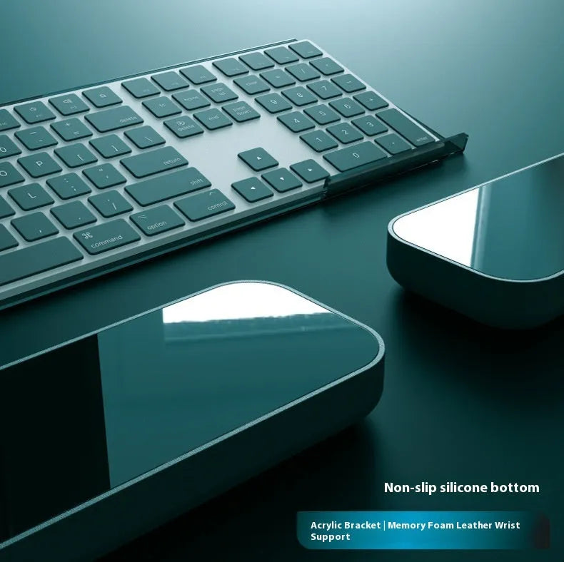 Double-sided black and grey keyboard mouse pad with wrist strap and hand pillow on a desk.