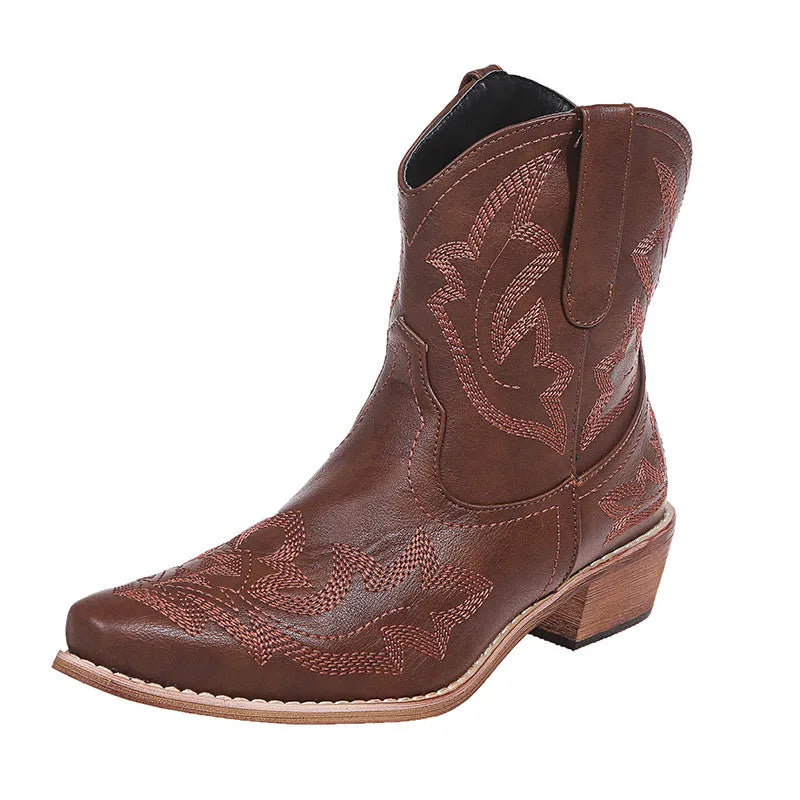 Blue women's cowboy ankle boots with embroidery and a low wedge heel on a wooden floor.