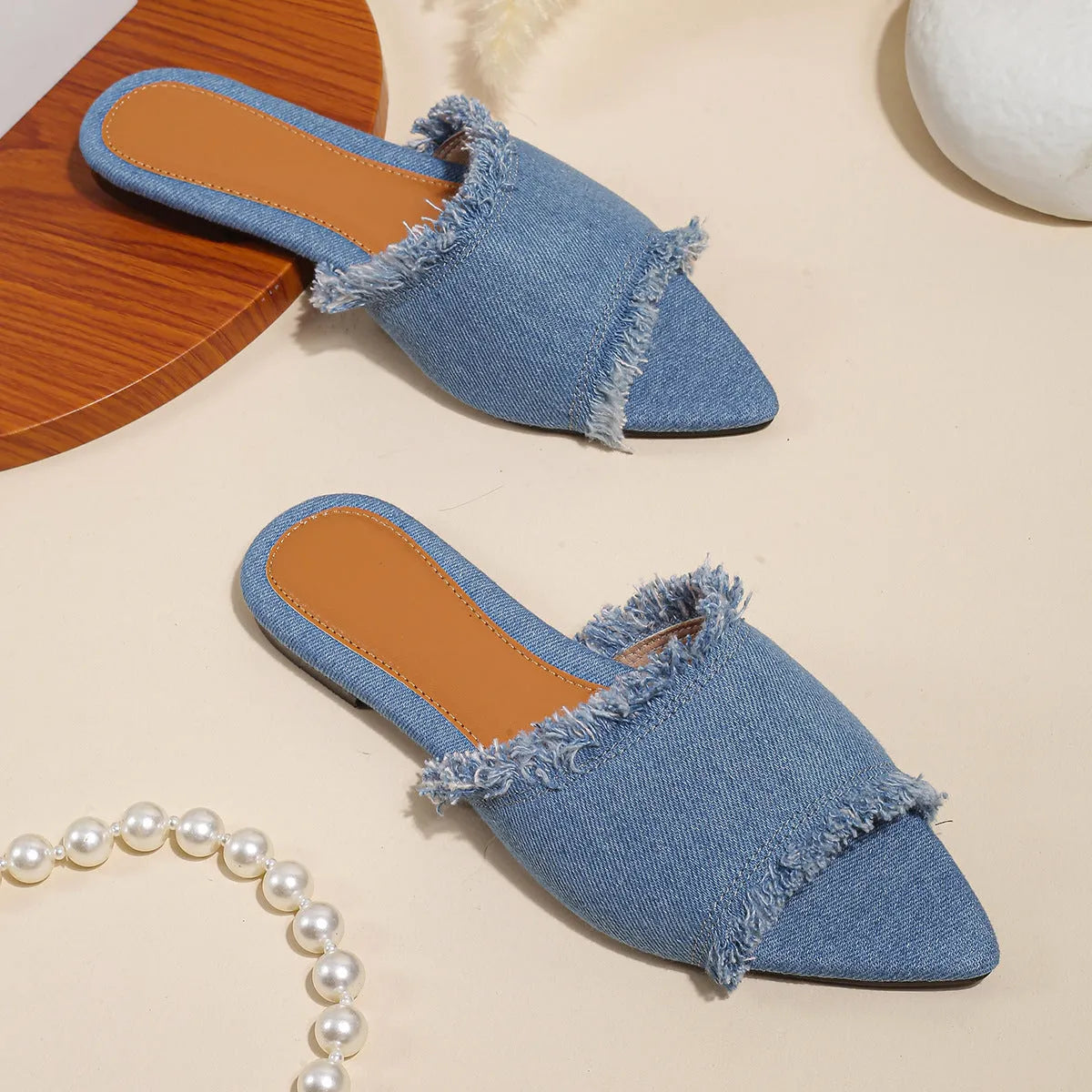 Women's denim flat slippers with tassel detail in apricot colour, showing leather lining.
