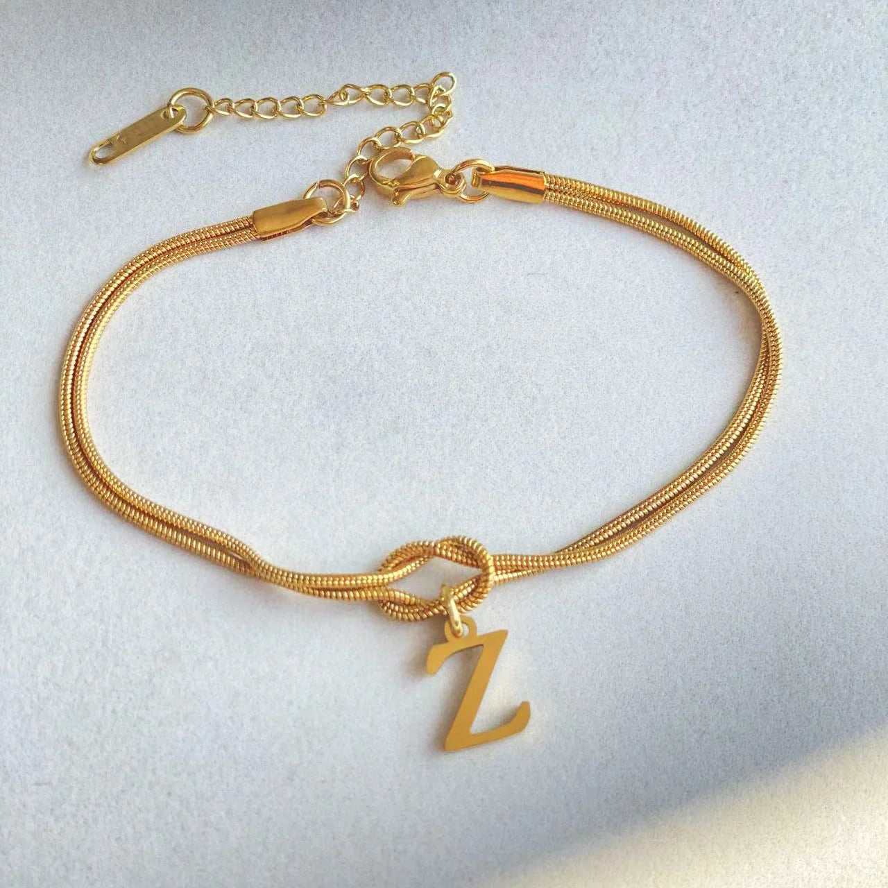 Elegant letter charm bracelets for women in gold and silver tones, featuring a delicate snake chain design and personalised letter charms.