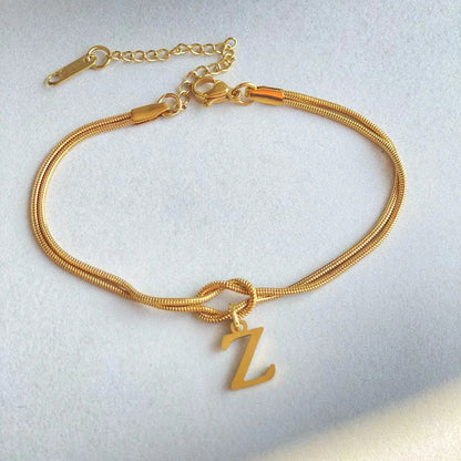 Elegant letter charm bracelets for women in gold and silver tones, featuring a delicate snake chain design and personalised letter charms.