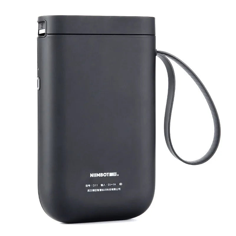 D11 black Bluetooth thermal label printer on a desk next to a smartphone showing the label design app