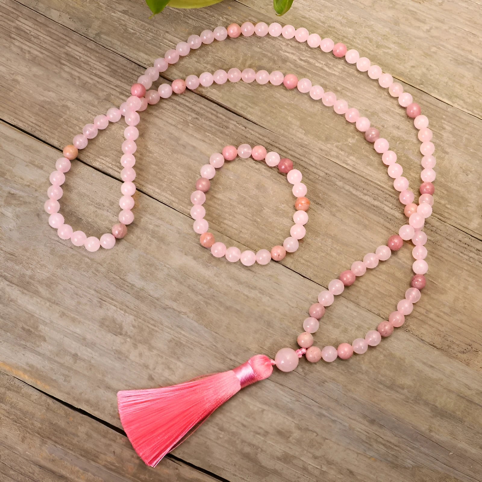 Natural stone bead necklace and bracelet set with a long fringe tassel pendant on a table.