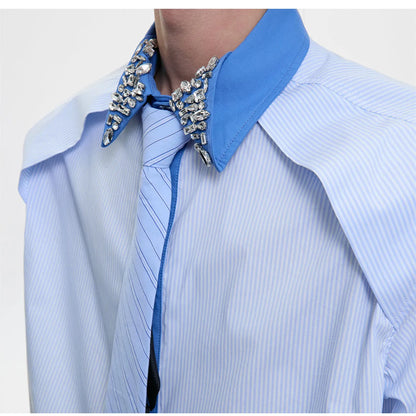 Man wearing a blue loose fit men's shirt with a diamond tie collar and patchwork striped design.