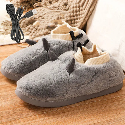 USB heating slippers in black plugged into a laptop, showing the cable and soft velvet upper.