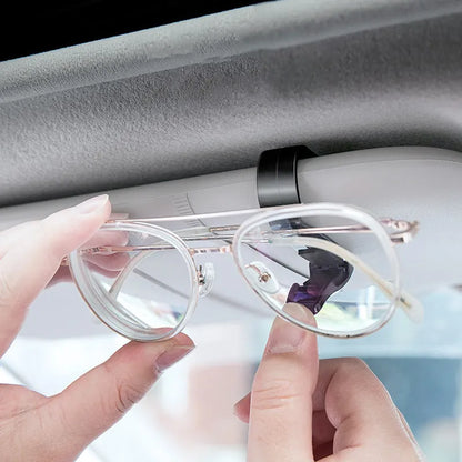 Black plastic clip for car sunshades to hold tickets, ID cards, or glasses.