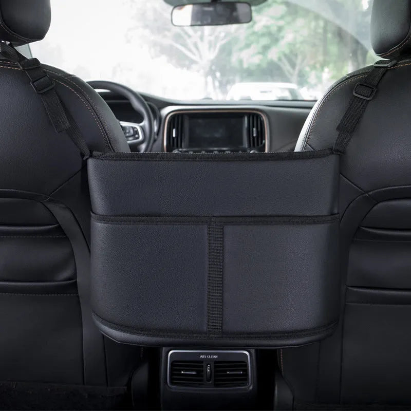 Black leather car seat gap storage bag hanging from armrest with tissue box, showing textured grain detail.