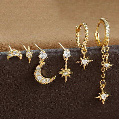 Set of six gold-coloured XINGX chain tassel stud earrings with zircon details on a flat surface.