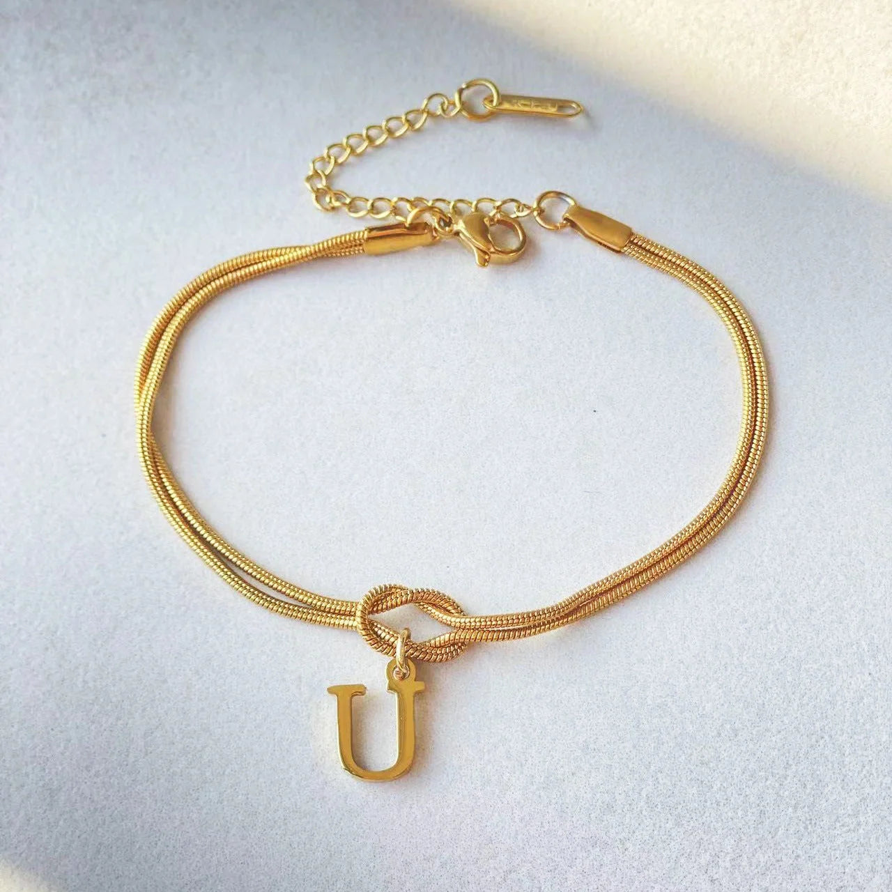 Elegant letter charm bracelets for women in gold and silver tones, featuring a delicate snake chain design and personalised letter charms.