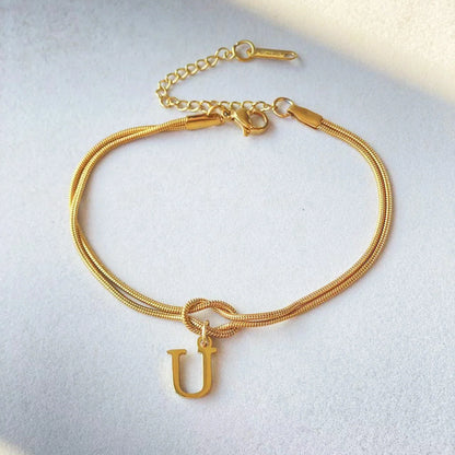 Elegant letter charm bracelets for women in gold and silver tones, featuring a delicate snake chain design and personalised letter charms.