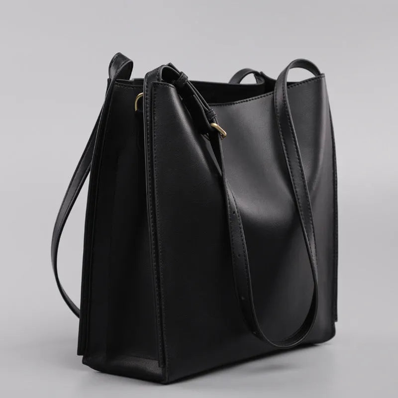 Brown genuine leather women's bucket-style commuter bag with double shoulder straps showing internal compartments