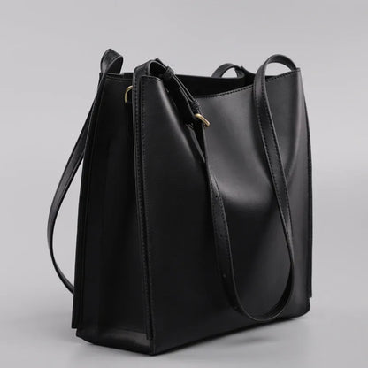 Brown genuine leather women's bucket-style commuter bag with double shoulder straps showing internal compartments