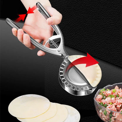 Silver stainless steel manual dumpling press with hinged handles on a wooden kitchen surface.