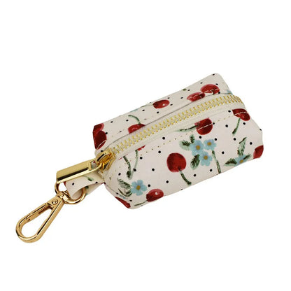 Red cherry printed dog collar with light gold buckle and matching leash, bow, vest and poop bag holder set