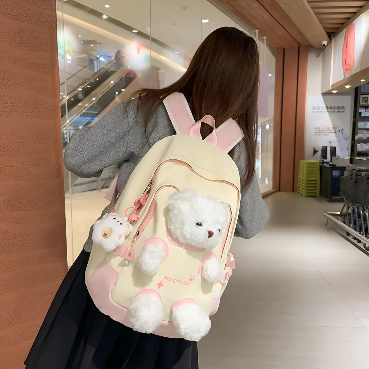 Macaron colour nylon school backpack with curved straps, shown in yellow pink, with a pendant attached.