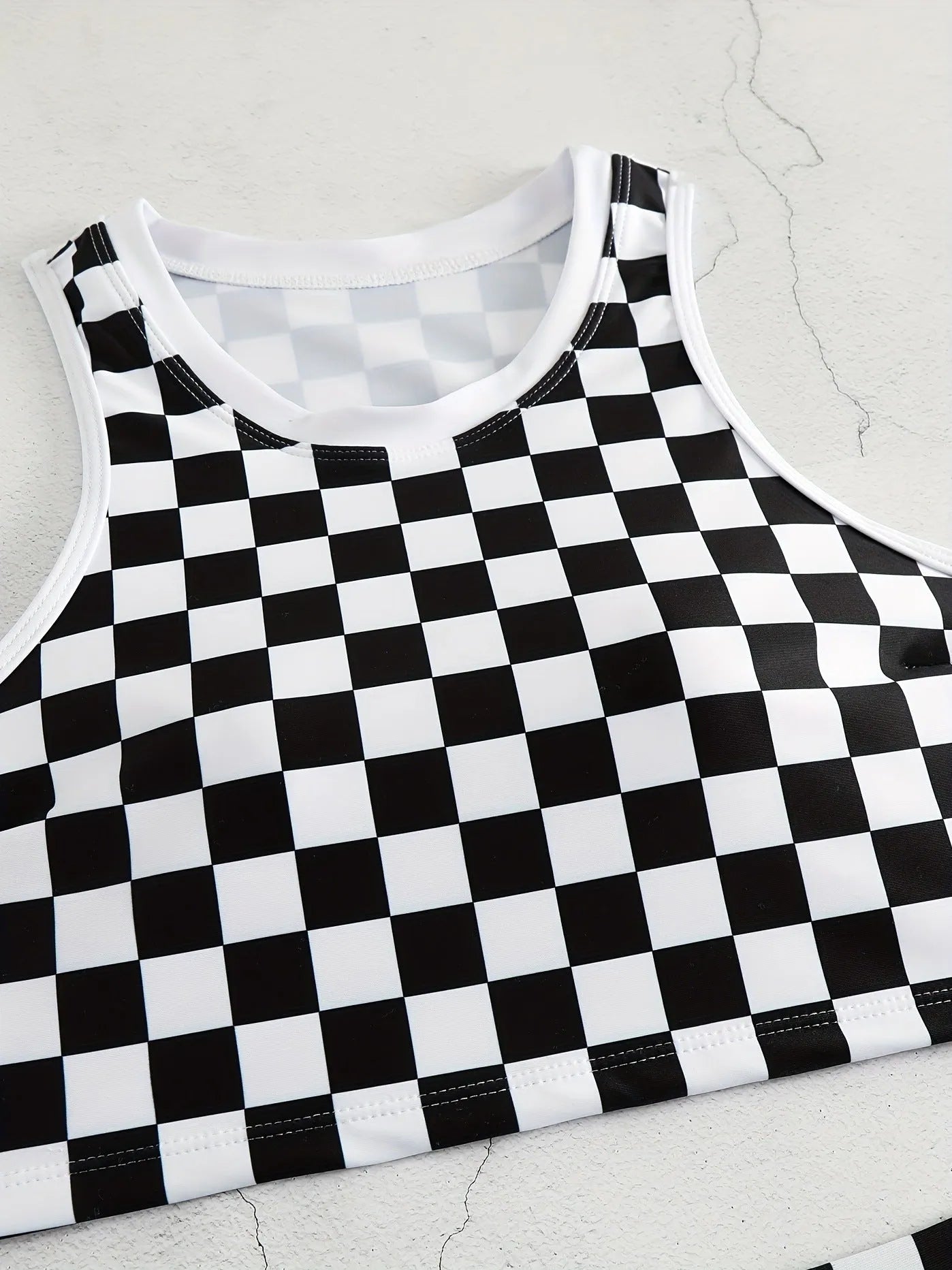 Women's checkerboard print backless one-piece swimsuit with suspender straps for swimming.