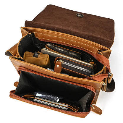 Men's brown first layer cowhide leather shoulder bag with crossbody strap and visible sewing line details.