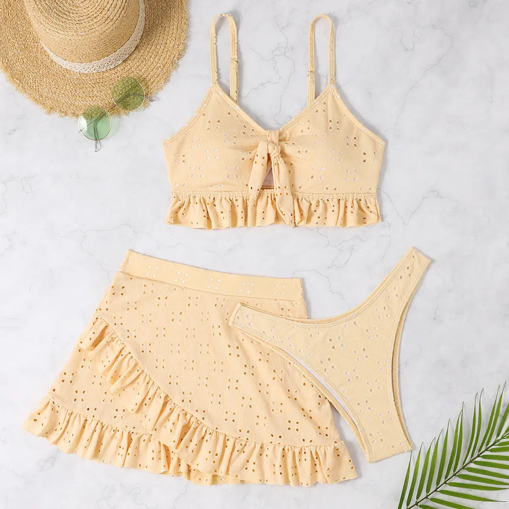 Women's solid colour three-piece bikini swimsuit with a split hip skirt.