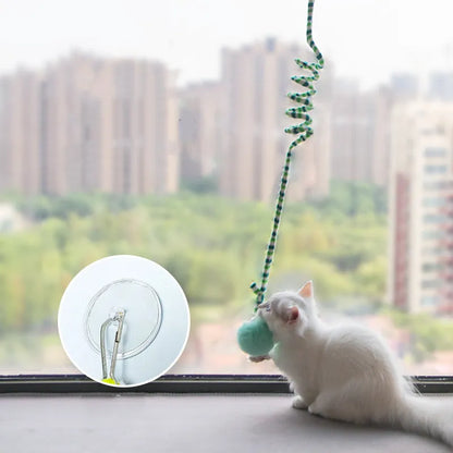 Hanging cat toy with spring, bell, and inflatable ball attached to a door via a suction cup.