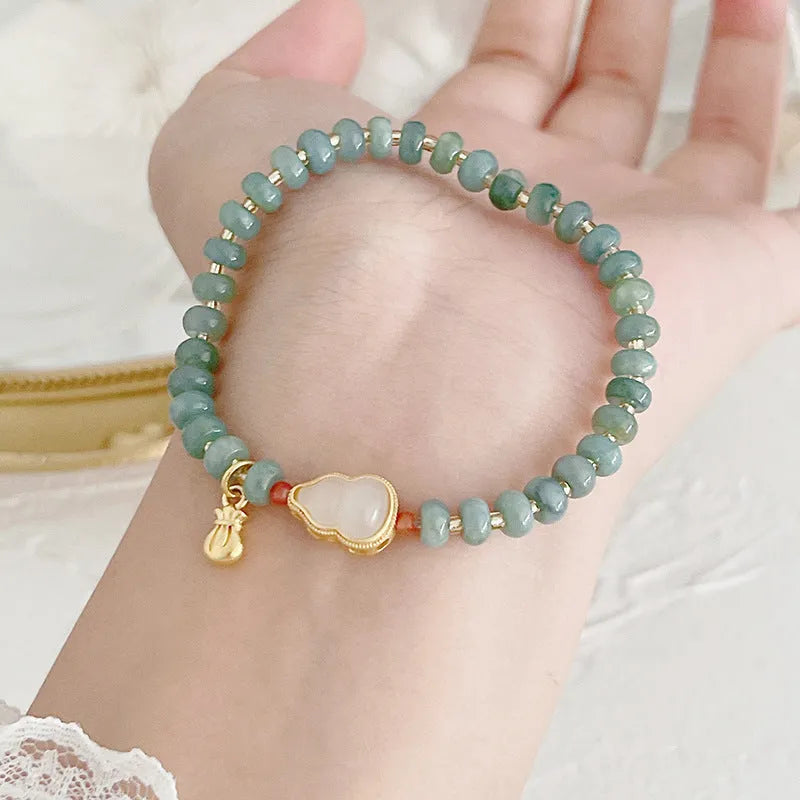 Simple blue jade bracelet with gourd charm, peace buckle, and adjustable cord on woman's wrist