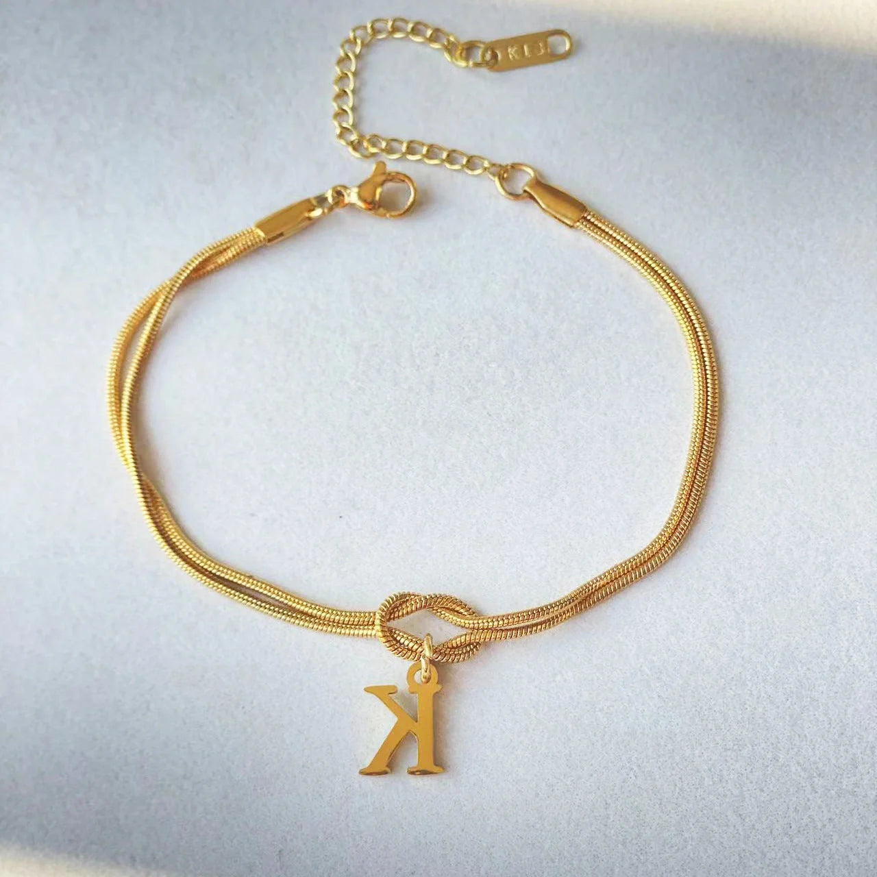 Elegant letter charm bracelets for women in gold and silver tones, featuring a delicate snake chain design and personalised letter charms.