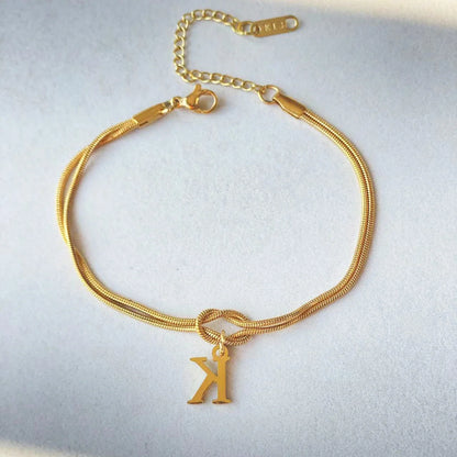 Elegant letter charm bracelets for women in gold and silver tones, featuring a delicate snake chain design and personalised letter charms.