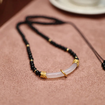 Close-up of a U-shaped necklace with frosted black agate, white chalcedony, and a 925 silver pendant on a beaded chain.