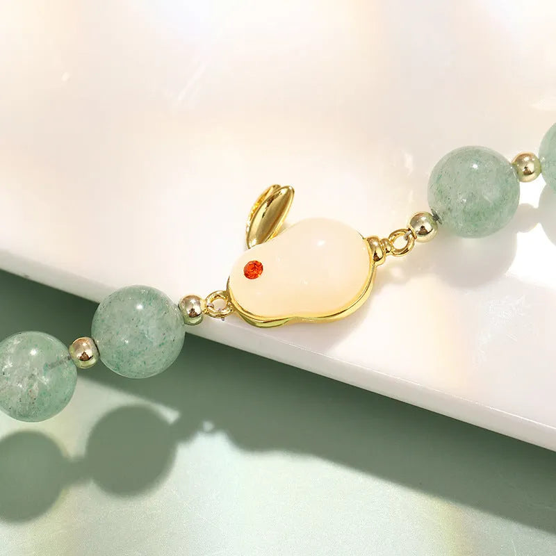 Adjustable rabbit charm bracelet with natural stone beads and gold plated details on a wrist.