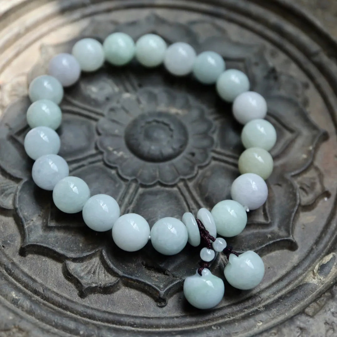 Natural green jade charm bracelet with carved apple and geometric stone pendants.
