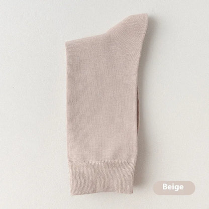 Pair of solid-colour men's mid-calf socks made from combed cotton on a wooden background