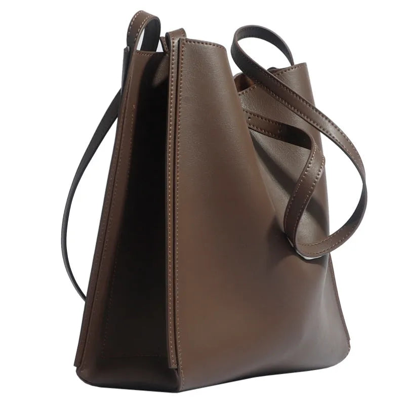 Brown genuine leather women's bucket-style commuter bag with double shoulder straps showing internal compartments