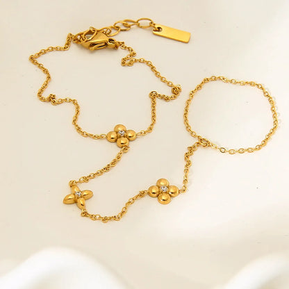 Gold stainless steel women's bracelet with geometric design of eight pointed stars and flowers.