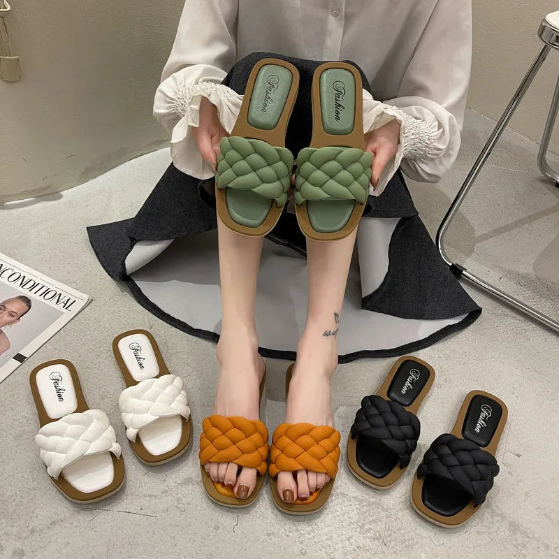 Women's white PVC beach sandals with a thick, patterned sole on a sandy background.