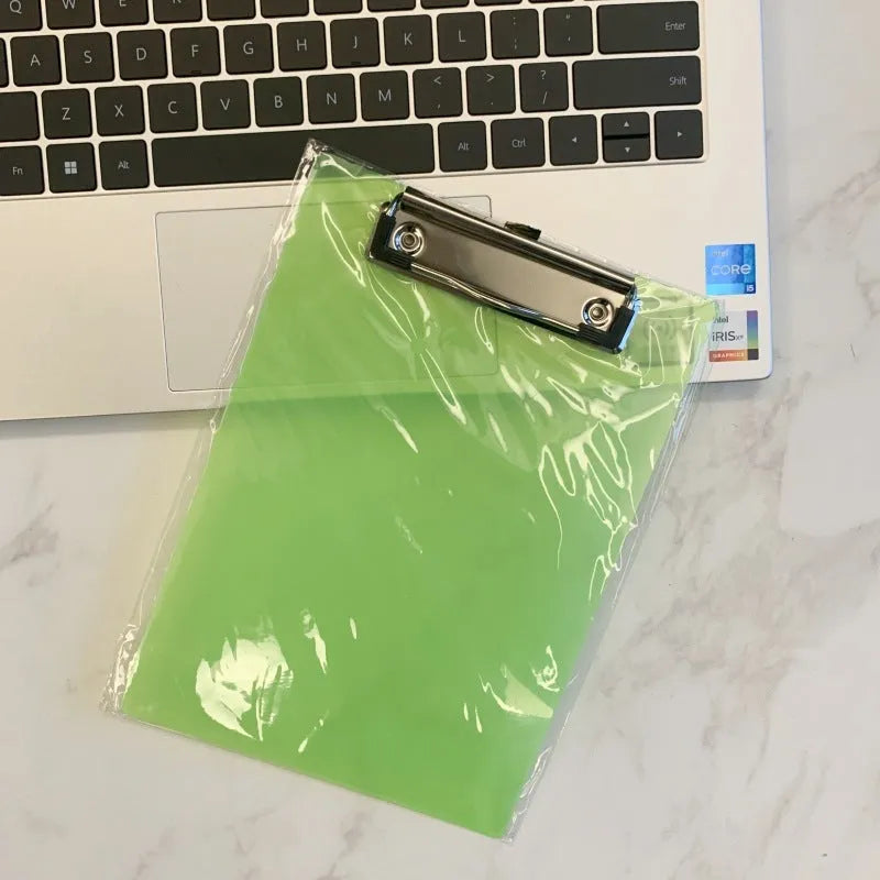 Transparent A4 plastic plate holder with metal clip, holding white paper, on a desk.