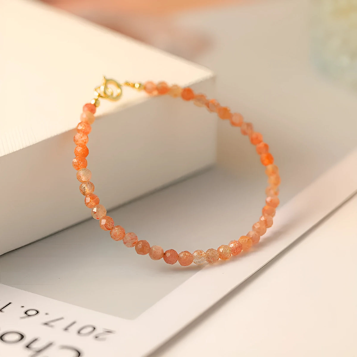 Women's ultra-thin 3mm Sunstone bead bracelet on wrist, showing natural crystal and delicate design.