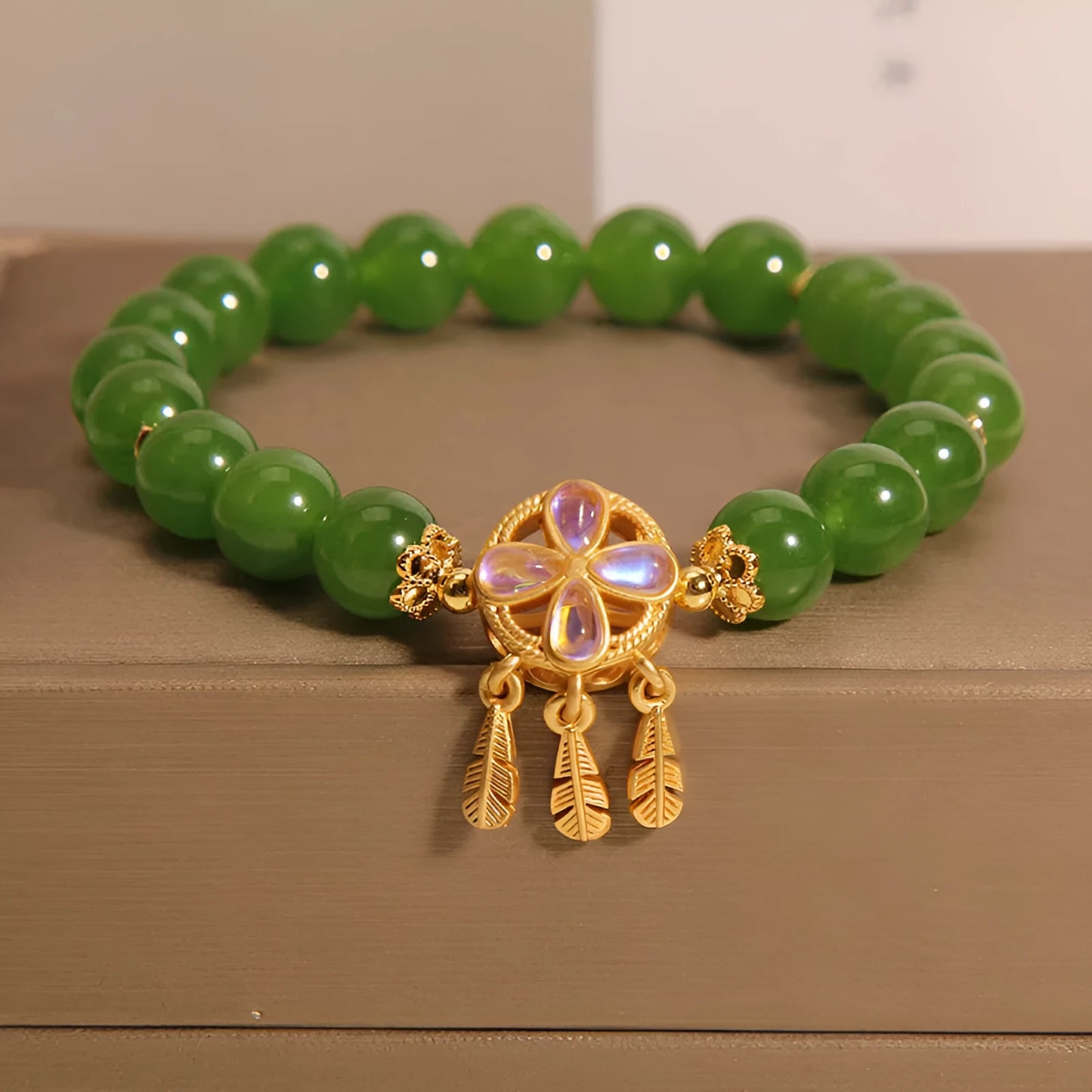 Green jasper crystal four-leaf clover dream catcher pendant on a women's bracelet.
