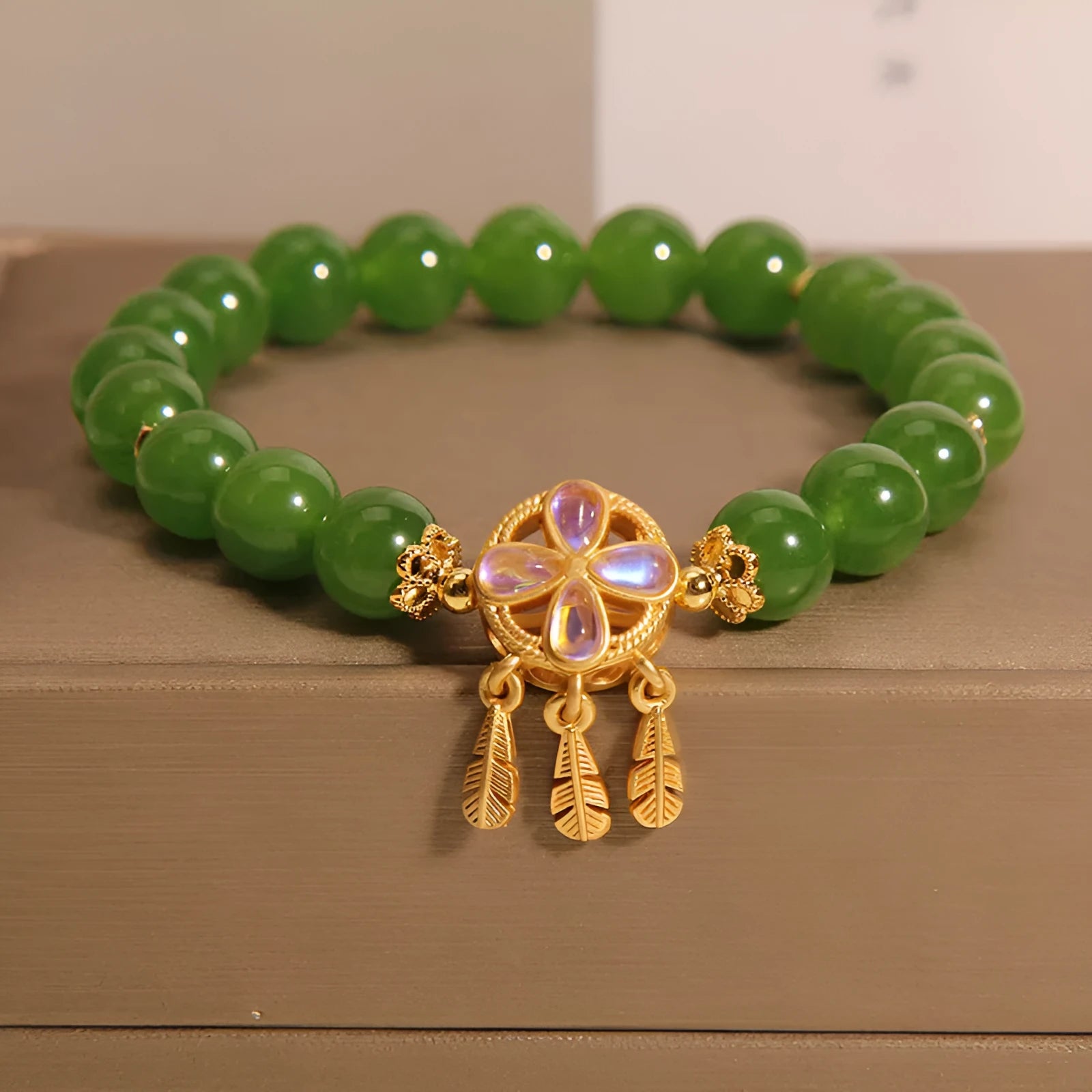 Green jasper crystal four-leaf clover dream catcher pendant on a women's bracelet.