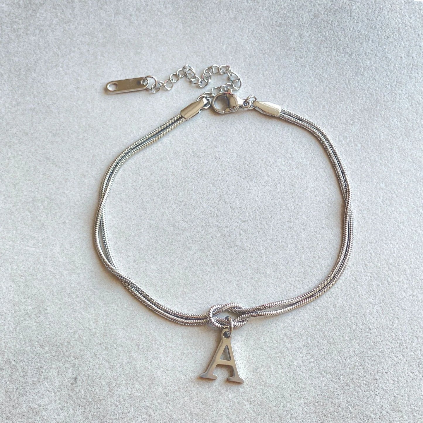 Elegant letter charm bracelets for women in gold and silver tones, featuring a delicate snake chain design and personalised letter charms.