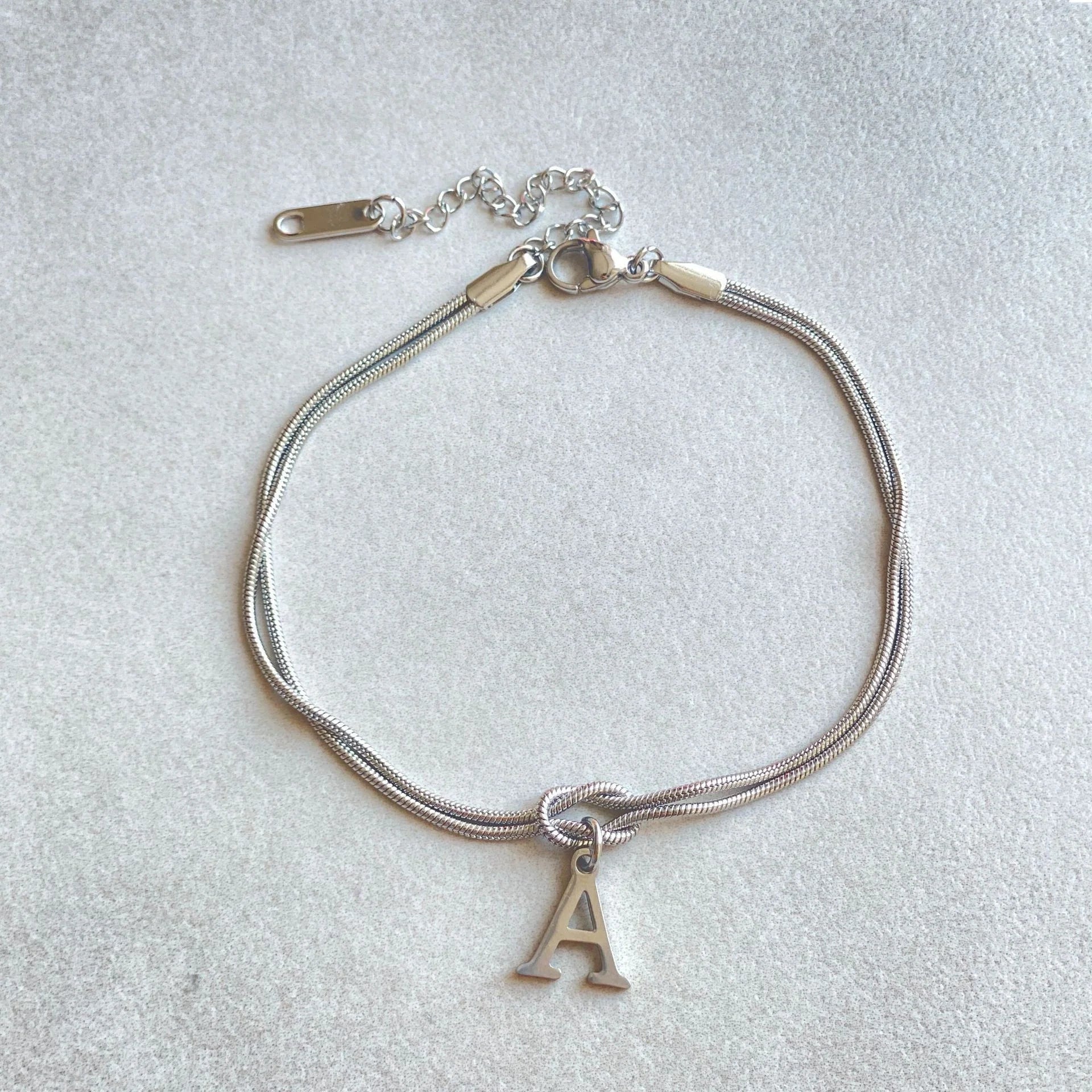 Elegant letter charm bracelets for women in gold and silver tones, featuring a delicate snake chain design and personalised letter charms.