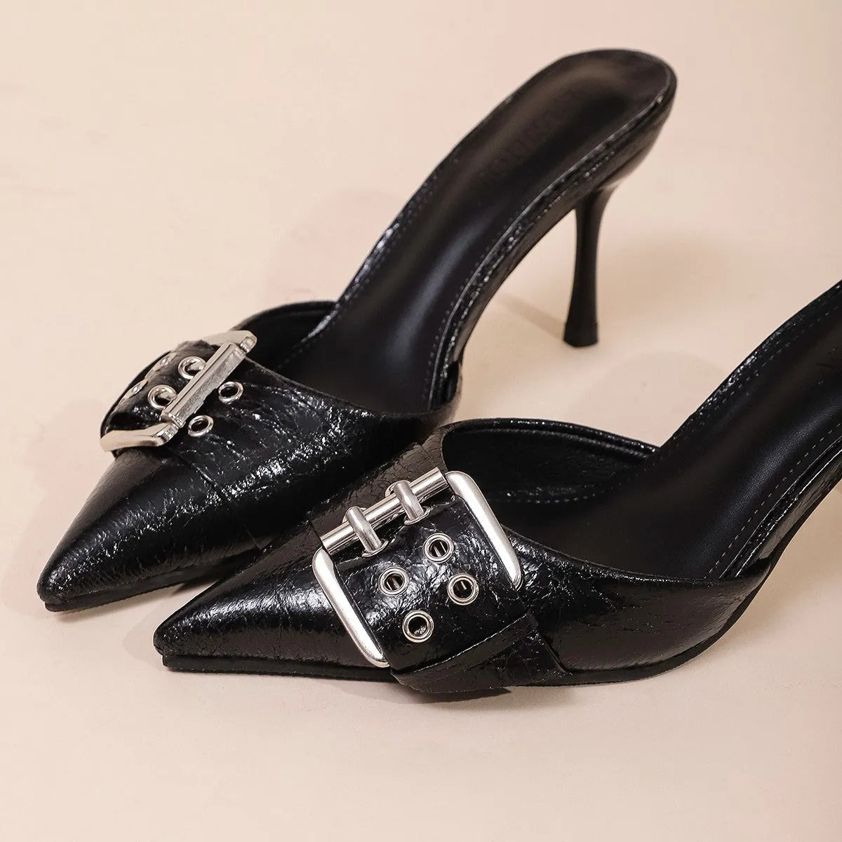 Black women's high heels with pointed toe, ankle strap, and decorative buckle.