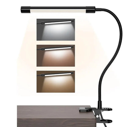 Black adjustable gooseneck desk lamp with USB cable bent over a notebook on a wooden desk.