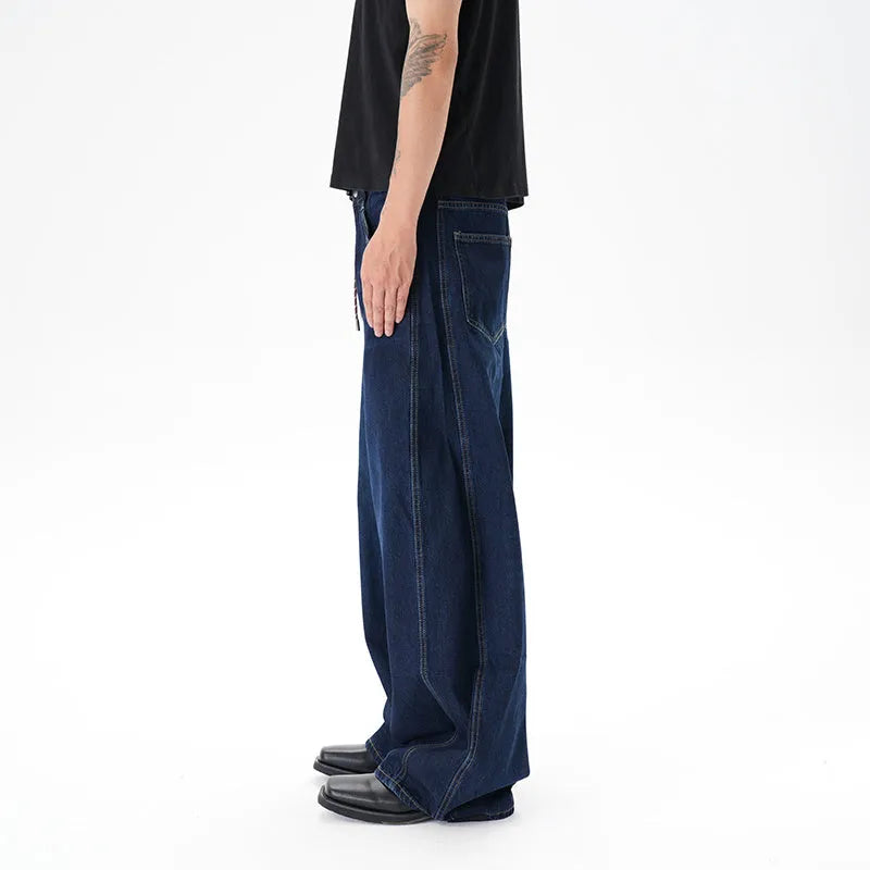 Dark blue distressed wide leg Machete jeans laid flat, showing washed denim texture.