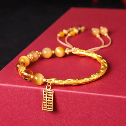 Women's handmade beaded bracelet with diamond-shaped tigereye and citrine abacus tag, yellow tower crystals, and copper details.