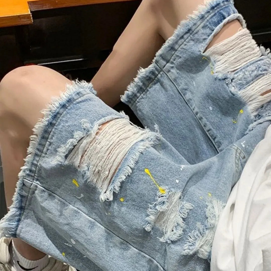 Man wearing loose-fit light blue water-washed denim shorts with a fifth pants length, showing street style.