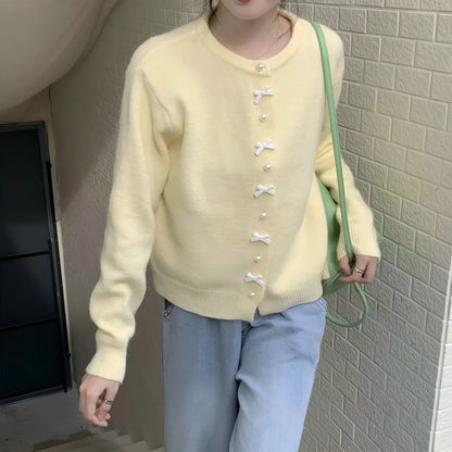 Women's acrylic cardigan sweater with pearl button bow detail in light yellow colour