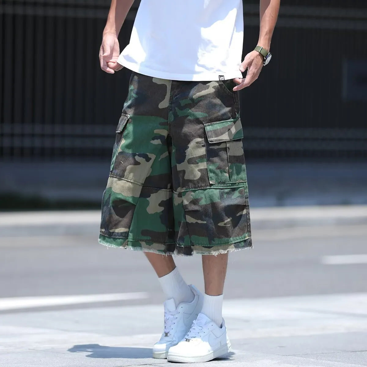 Man wearing loose-fit cropped camouflage shorts in a retro workwear style.