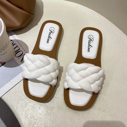 Women's white PVC beach sandals with a thick, patterned sole on a sandy background.