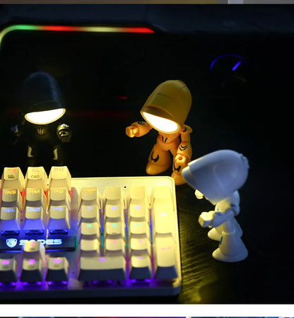 Mini mecha robot hero LED night light with adjustable arms on a desk.